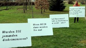 Ursula Zitzler mit Plakaten gegen Rassismus auf einer Wiese