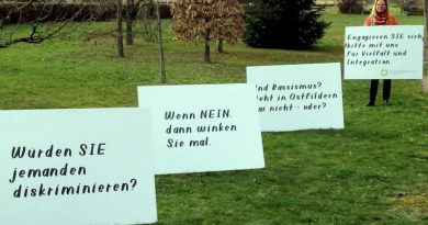 Ursula Zitzler mit Plakaten gegen Rassismus auf einer Wiese