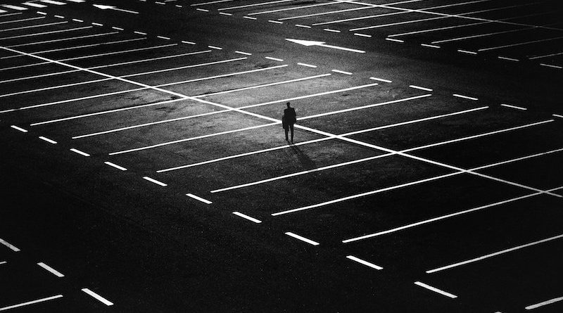 Mann nachts allein auf leerem Parkplatz