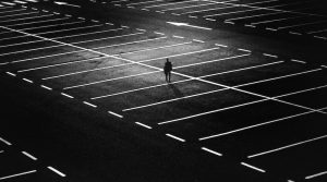 Mann nachts allein auf leerem Parkplatz