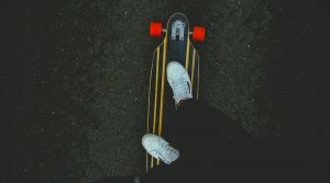 Zwei Beine und weiße Turnschuhe auf Skateboard