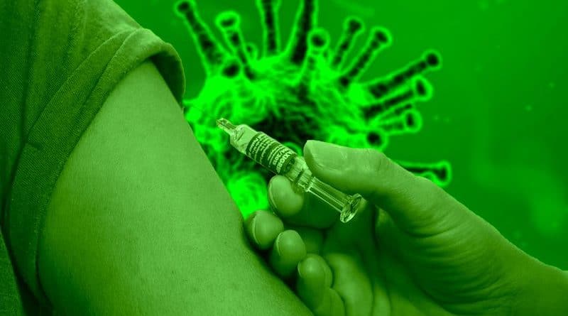 Hand beim Impfen in Oberarm vor grünem Coronasymbol