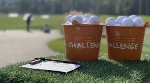 orange Eimer mit Golfbällen gefüllt vor Driving Range