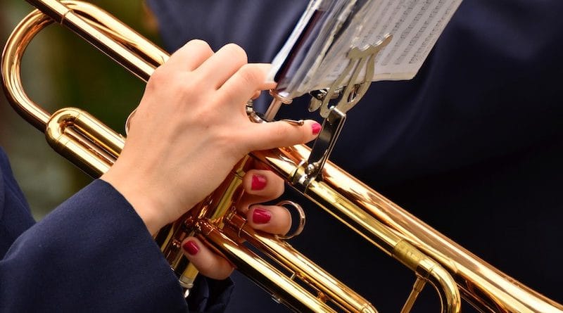 Frau mit rot lackierten Fingernägeln spielt Trompete