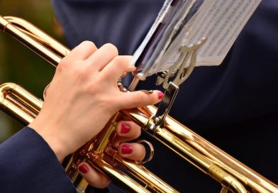 Frau mit rot lackierten Fingernägeln spielt Trompete