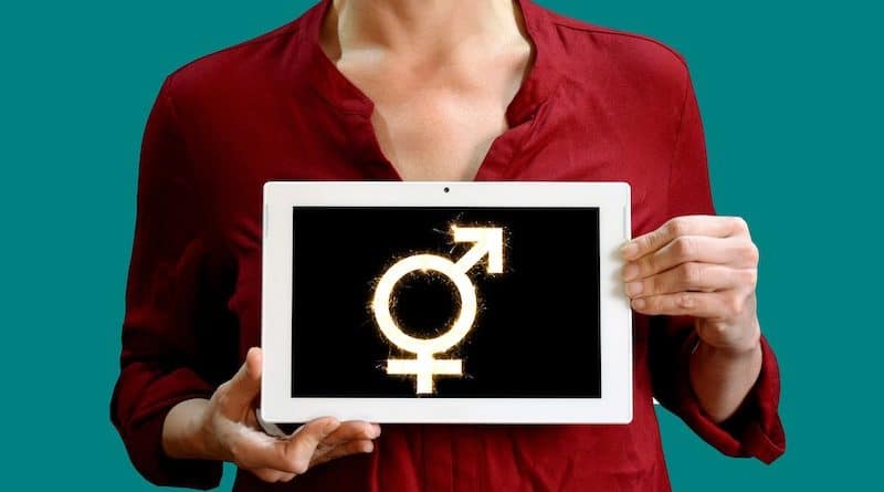 Frau hält Tafel mit kombiniertem männlich-weiblich-Symbol