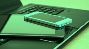 Smartphone auf Tablet auf Tastatur eines aufgeklappten Laptops