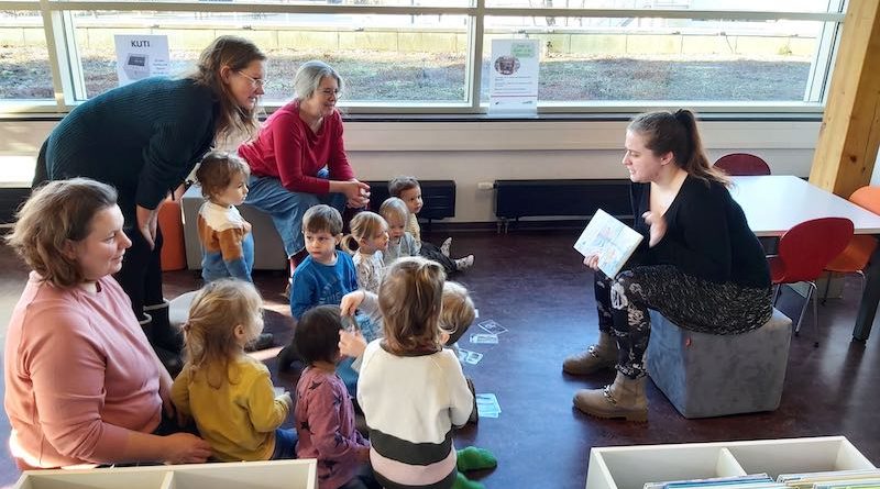 Tagesmütter mit Kindern bei einer Vorlesestunde in der Bücherei