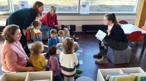 Tagesmütter mit Kindern bei einer Vorlesestunde in der Bücherei
