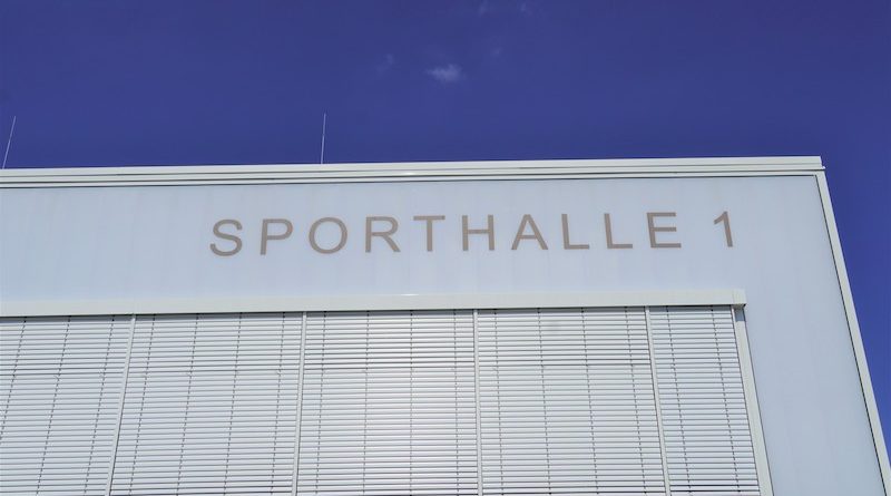 Sporthalle 1 Schriftzug an der Fassade vor blauem Himmel