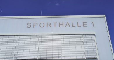 Sporthalle 1 Schriftzug an der Fassade vor blauem Himmel