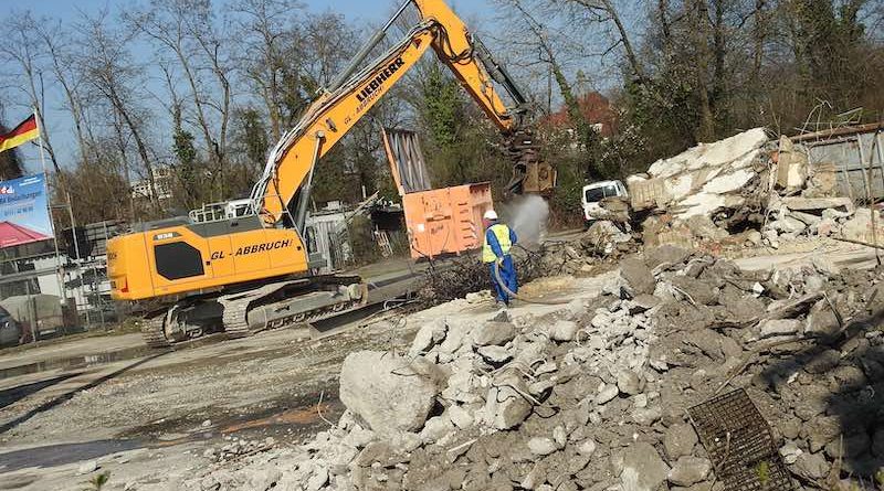 Gelber Bagger hinter Schuttbergen an der Wasenstraße 34 am 8.3.2024