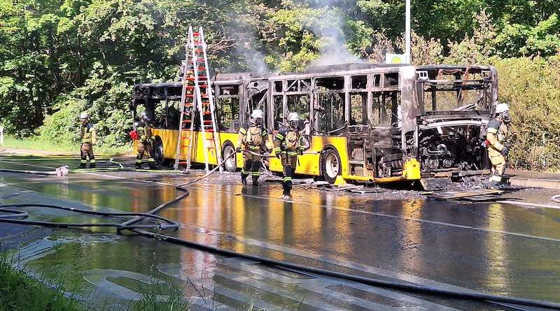 Feuerwehrleute nach Löscharbeiten an ausgebranntem Bus