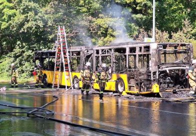 Feuerwehrleute nach Löscharbeiten an ausgebranntem Bus
