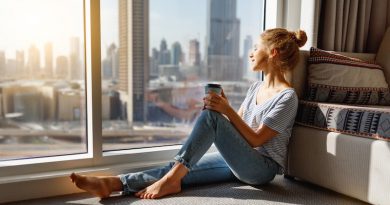 happy young woman drinks coffee in morning at big window