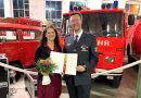 Suzana und Jan Steffen Chrobok bei Ehrung vor Feuerwehrfahrzeugen