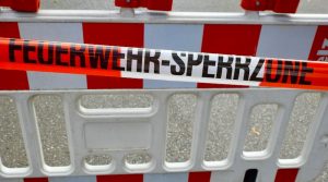 Absperrgitter auf der Straße hinter Feuewehr-Flatterband