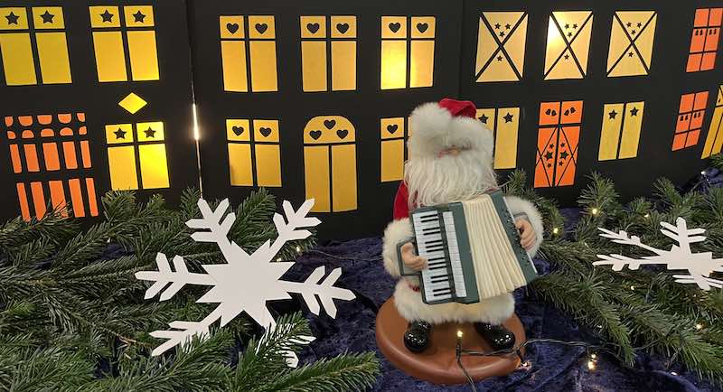 Nikolausfigur mit Handharmonika vor weihnachtlicher Häuserkulisse
