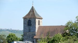 Foto der Michaelskirche in Stuttgart-Wangen bei blauem Himmel, im Hintergrund sieht man die Weinberge