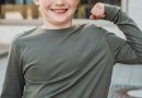 Junge zeigt Muskeln des linken Arms