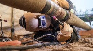 Arbeiter liegend bei Arbeiten an einer Wasserstoffleitung