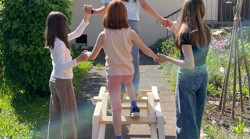 Kinder balancieren auf einem Holzgestell