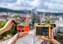 Zwei Notfallradios in Händen gehalten, dahinter die Innenstadt von Stuttgart