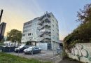 Wohnheim an der Inselstraße 33 hinter Maschendrahtzaun und parkenden Autos